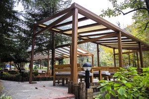 Wood-framed pergola with clear polycarbonate roof and bench seating, highlighting timber as a premium pergola material.